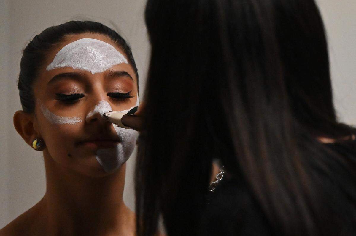 Elisa Aguirre (left) gets her face painted for her role as Harlequin Doll during dress rehearsal for the production of “The Nutcracker” on Tuesday, Dec. 9, 2025, at the Grand Opera House in Macon. 