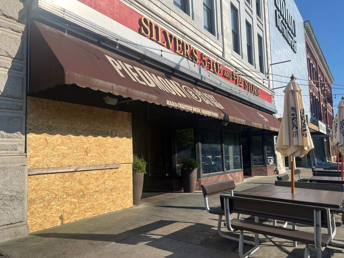 A wooden plaque covered a broken glass window after a brick was thrown in front of Piedmont Brewery July 11, 2024.