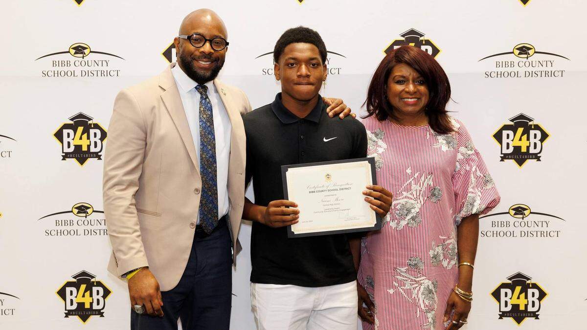 Bibb County School District Superintendent Dan Sims (left) and Bibb County board member Sundra Woodford (right) recognize Central High School student Naiem Moore for his leadership skills and community service while overcoming multiple barriers.