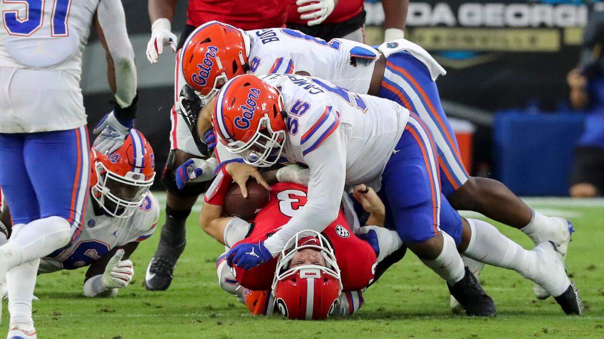 Georgia quarterback Stetson Bennett (13) is taken down at the line of scrimmage by Florida defensive lineman Kyree Campbell (55) during the first half of a NCAA college football, Saturday, Nov. 7, 2020, in Jacksonville, Fla. (Curtis Compton/Atlanta Journal-Constitution via AP)