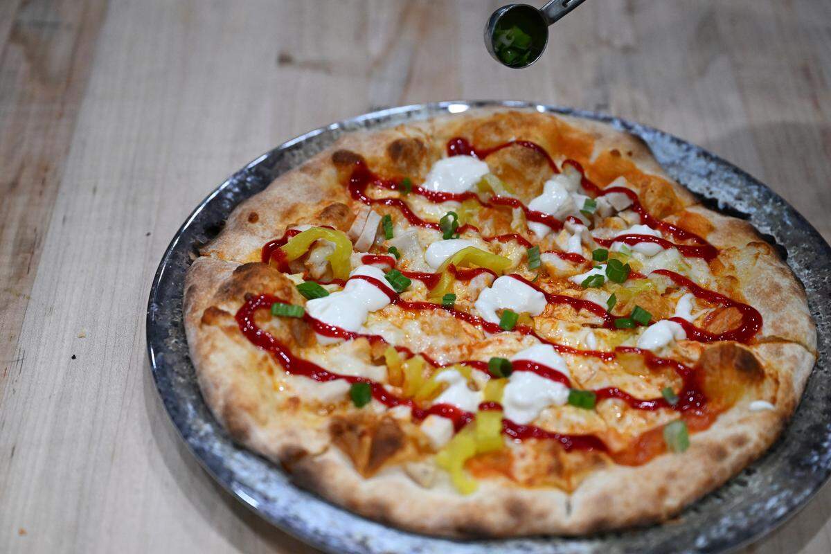 Onions being added on top of the Buffalo Chicken pizza from Smokin’ Oak Wood-Fired Pizza and Taproom in Warner Robins.