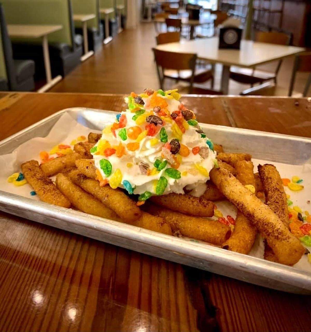A fair favorite, but with a twist. These Funnel Cake Fries are topped with powdered sugar, whipped cream, and fruity pebbles.