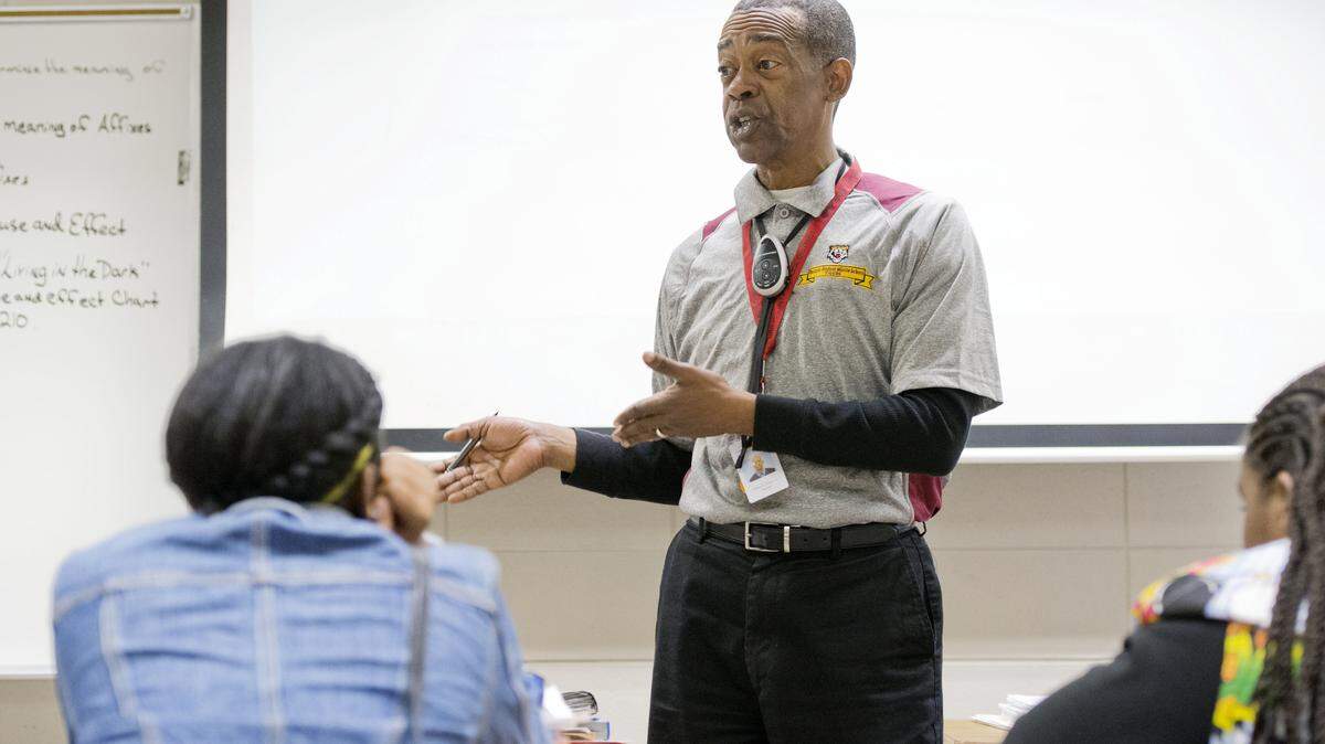 Ballard-Hudson Middle School seventh-grade teacher Walter Grant has a discussion Friday with his class prior to a test. Grant is wearing an infrared teardrop microphone that is used with the school's monitoring system.