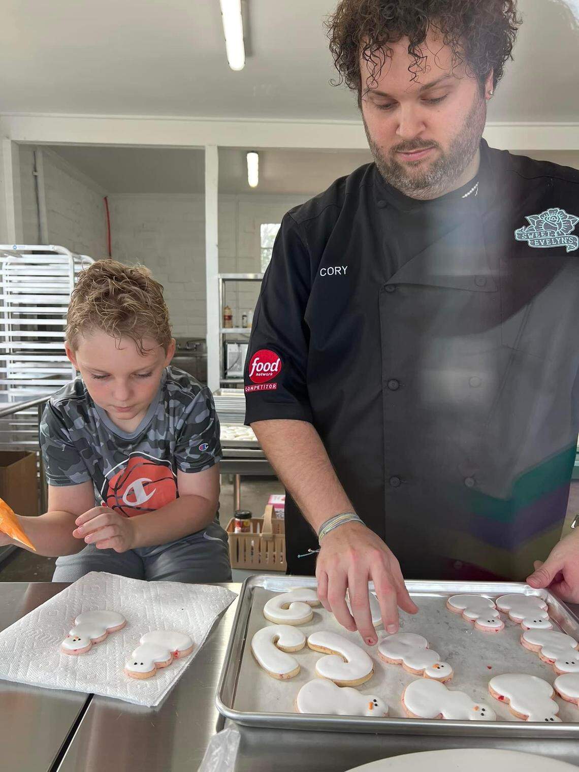 Cory Jones, an industry professional cookie artist and owner of Sweet Evelyn’s, right, decorates cookies with Brannen McIntyre, son of Jones’ close friend Brandi McIntyre.