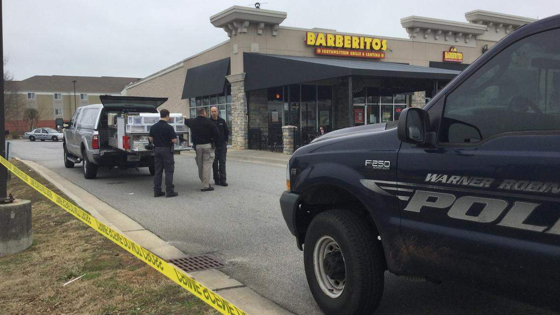 Two Warner Robins crime scene investigators talk Monday with a Houston County sheriff’s investigator outside Barberitos at 3123 Watson Blvd., where a restaurant worker was slain and another shot in the head during an armed robbery Sunday night. The injured worker is recovering at the Medical Center, Navicent Health, police said.
