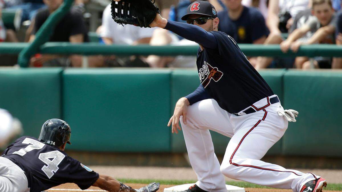 New York Yankees' Ronald Torreyes (74) dives back to first ahead of the throw to Atlanta Braves first baseman Freddie Freeman, right, in a pick off attempt in the first inning of a spring training baseball game, Wednesday, March 30, 2016, in Kissimmee, Fla. (AP Photo/John Raoux)