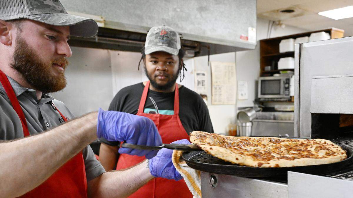 My Father’s Place co-owner Jacob Kline (left) pulls a buffalo chicken pizza out of the oven during staff training on Tuesday, Aug. 19, 2025, at My Father’s Place in Warner Robins, Georgia. The buffalo chicken pizza is expected to be added to the menu after its successful debut at the grand reopening Saturday, Aug. 23, 2025.