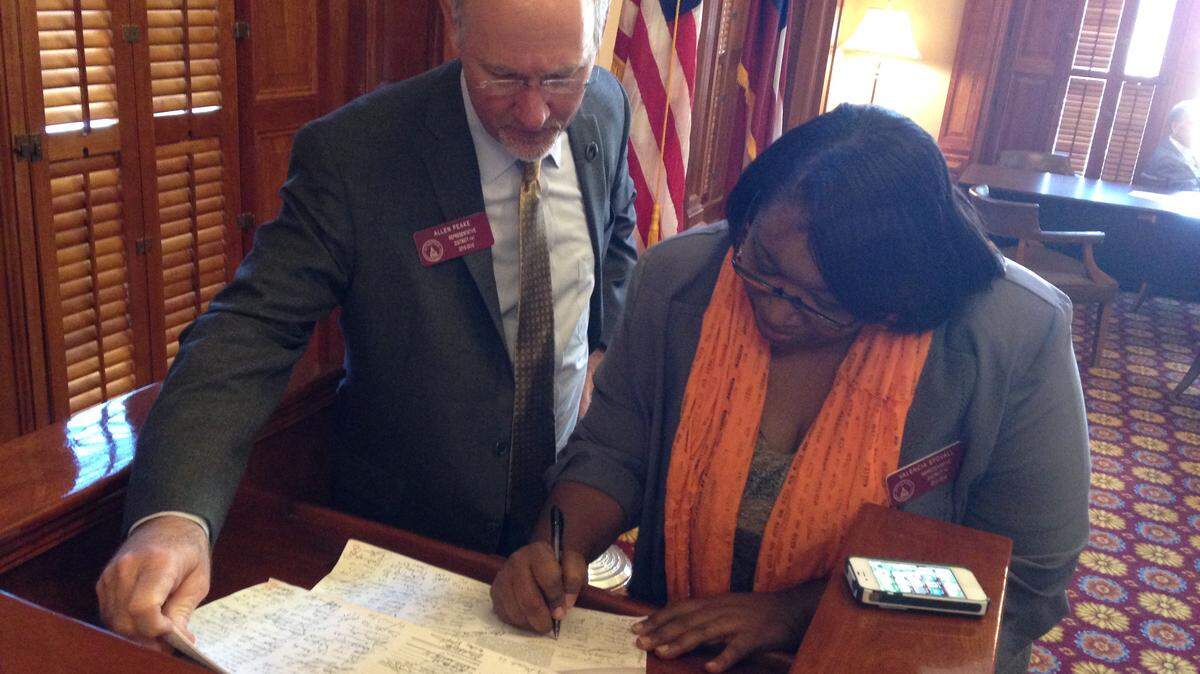 State Rep. Valencia Stovall, D-Lake City, signs a Georgia medical cannabis cultivation bill as its sponsor, state Rep. Allen Peake, R-Macon, looks on. A majority of House members had signed Peake's bill as of Jan. 12.
