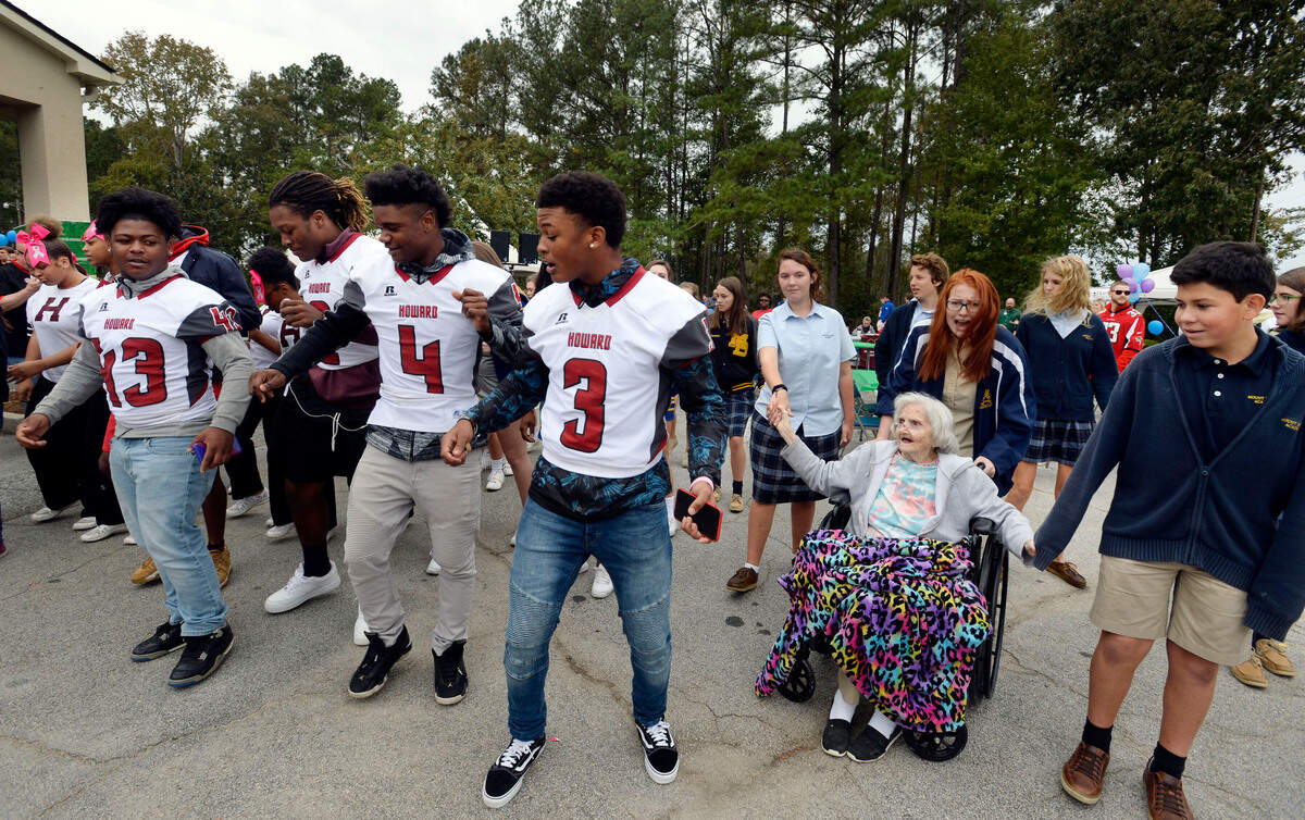 Bolingreen Health and Rehabilitation resident Beverly Smith, at right, gets some help from Mt. De Sales students Lawson Thigpen, Mollie Craig and Jose Morales as she keeps up with dancing Howard High School football players during the home’s annual tailgate party in October. About 150 students from four high schools and three marching bands joined the seniors for lunch, conversations about football, and fellowship as the season rolls into it’s zenith.