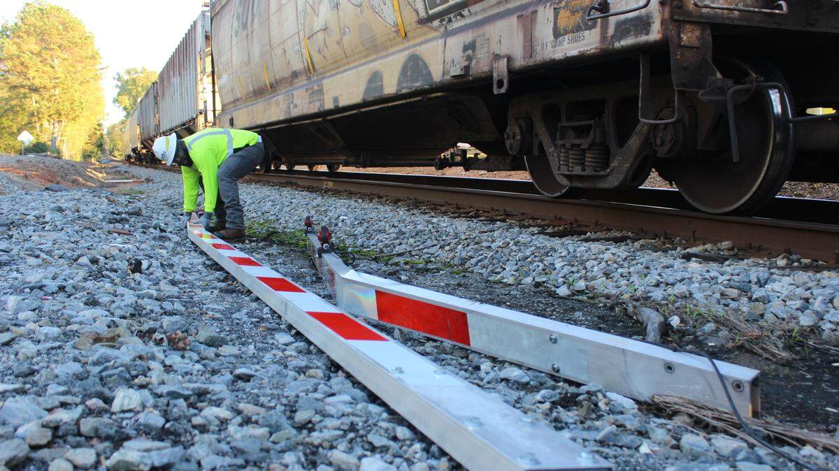 A Norfolk Southern railroad company employee lifts a damaged crossing gate after a train crashed into an SUV on Tucker and Forsyth roads in Macon, Ga. on Friday, Nov. 15, 2024.