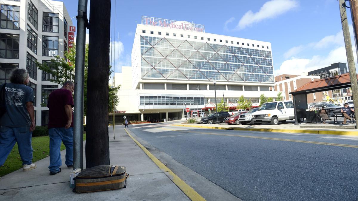 People passing by the Macon Transit Authority bus stop in front of the Medical Center, Navicent Health, on July 5, don't bother a suitcase left there. The Macon-Bibb County commissioners cut funds for indigent care to the hospital in the most recent revised budget.