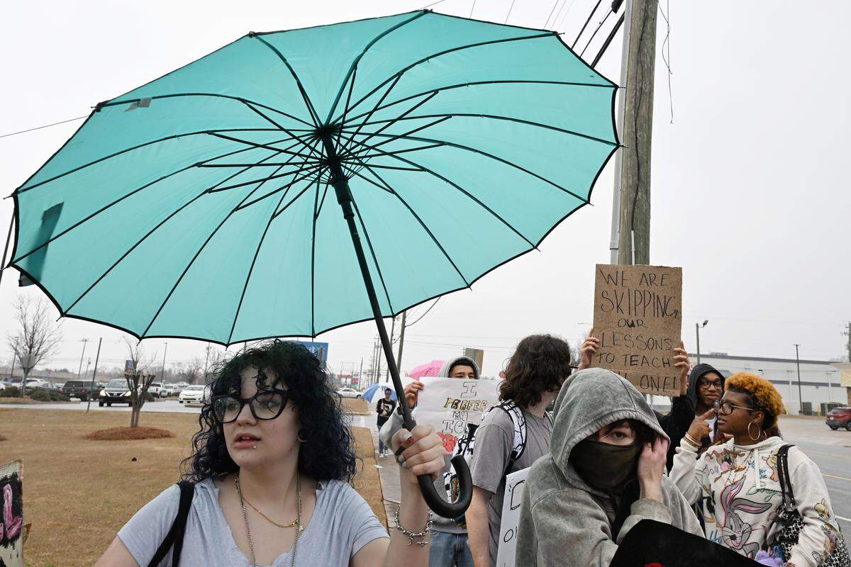 Northside High School student Wyatt Faiella, 18, holds an umbrella while walking along North Houston Road to protest  U.S. Immigration and Customs Enforcement (ICE) on Friday, Jan. 23, 2026, in Warner Robins, Georgia. Around a dozen Northside students as well as community members marched to protest recent practices by ICE under the Trump administration.