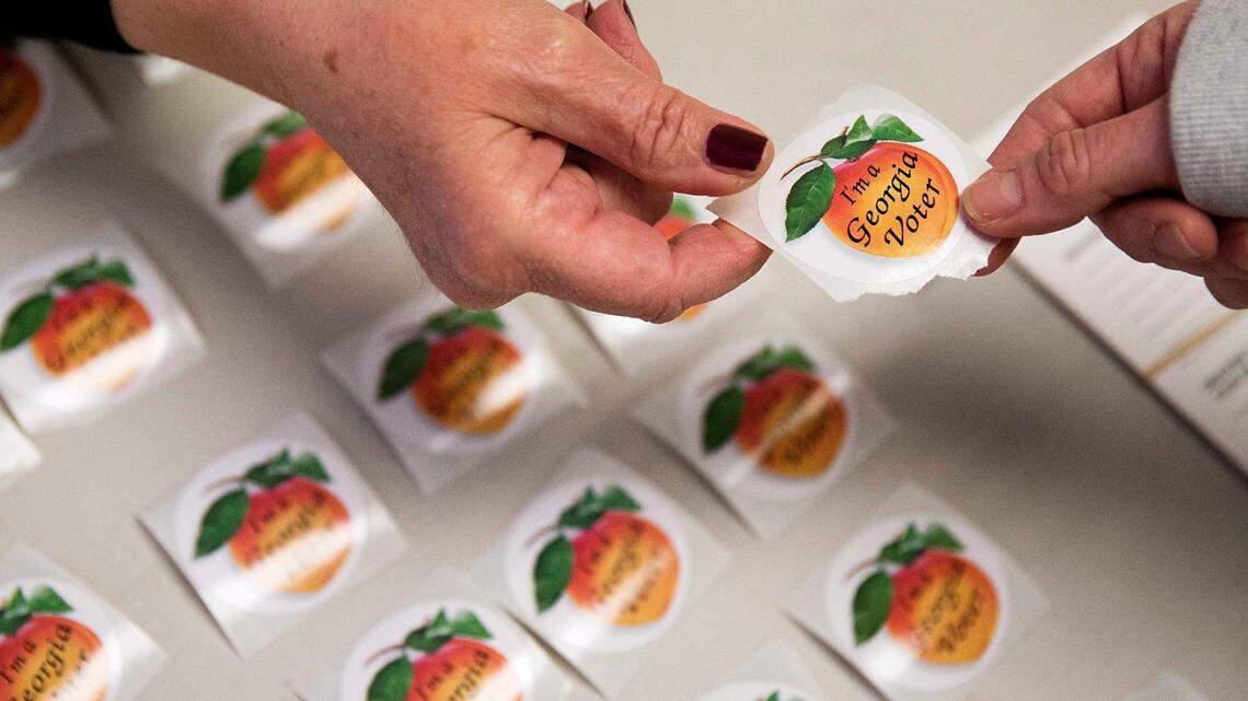 FILE - In this March 1, 2016 file photo, poll worker Delores Peterson, left, hands a sticker to a voter after they casted their ballot in Georgia’s primary election at a polling site in Atlanta. Lawmakers in Georgia and across the country have introduced bills to put more restrictions on absentee voting following hte 2020 election. (AP Photo/David Goldman)