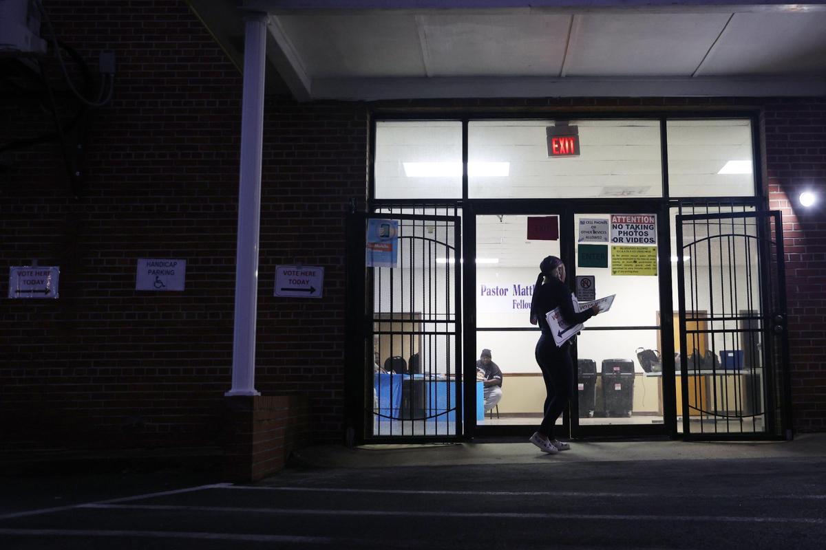 Poll worker Dominique Stroud walks inside after hanging voting posters on the wall outside of polling location Beulah Missionary Baptist Church before polls opened for Election Day on Tuesday, Nov. 5, 2024, in Macon, Georgia. Polls in Macon are opened from 7 a.m. to 7 p.m. today.