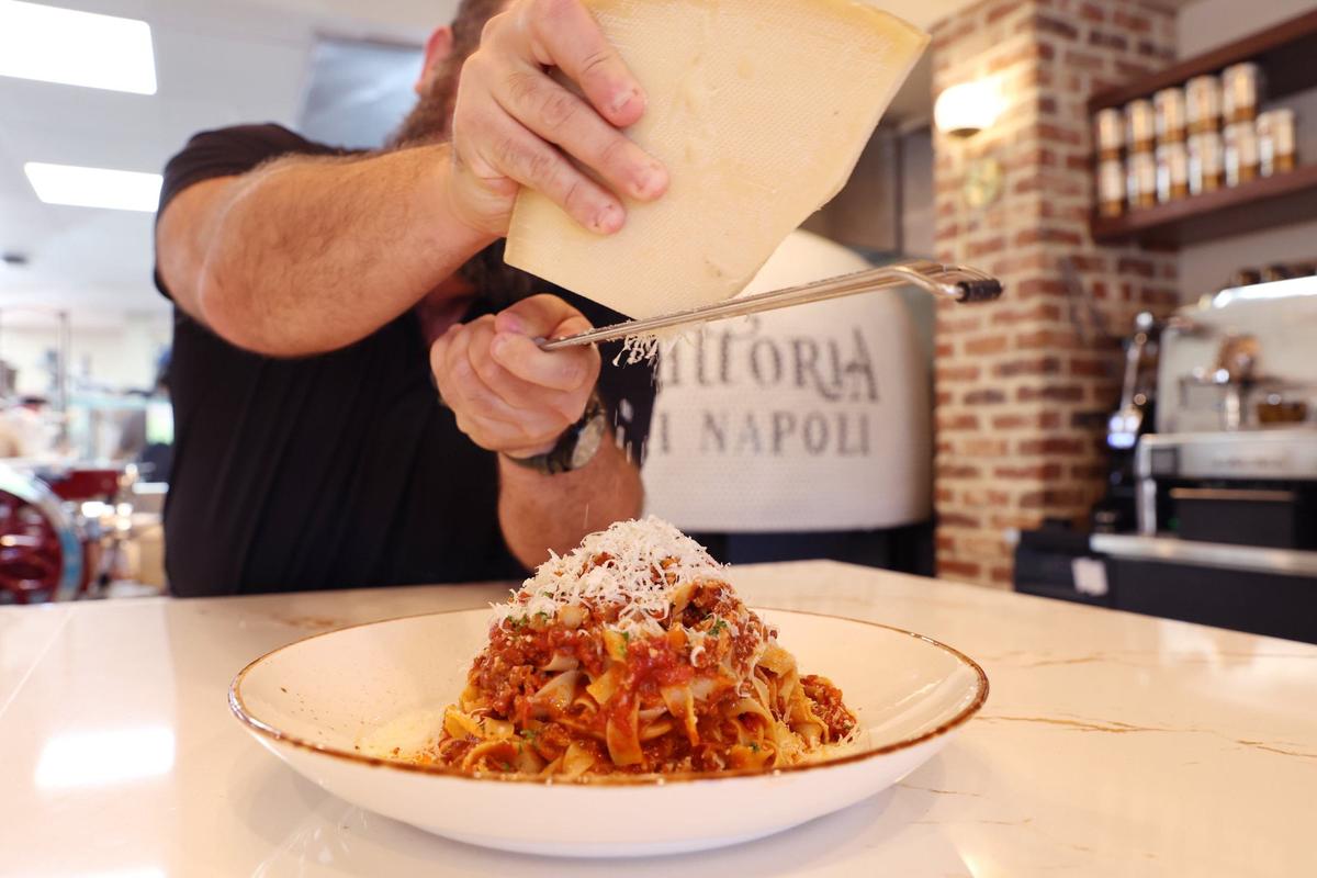John Staurulakis, the proprietor of Trattoria di Napoli, grates Grana Padano Italian cheese onto the new Italian restaurant’s fettuccine bolognese on Wednesday, Aug. 7, 2024, in downtown Perry. The restaurant opens soon.