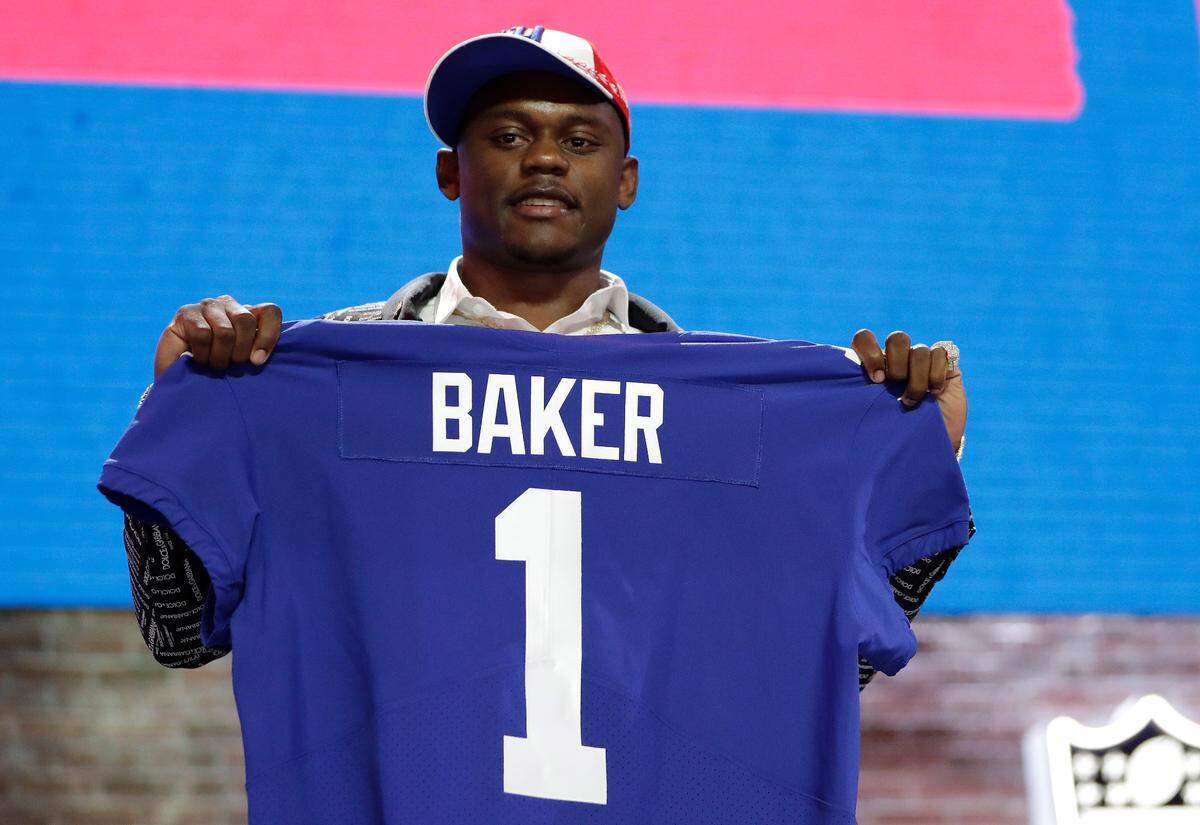FILE - In this April 25, 2019, file photo, Georgia defensive back DeAndre Baker poses with his new jersey after the New York Giants selected him in the first round at the NFL football draft in Nashville, Tenn. Police in South Florida are trying to find Giants cornerback Baker and Seattle Seahawks cornerback Quinton Dunbar after multiple witnesses accused them of an armed robbery at a party. Miramar police issued arrest warrants for both men Thursday, May 14, 2020. (AP Photo/Mark Humphrey, File)