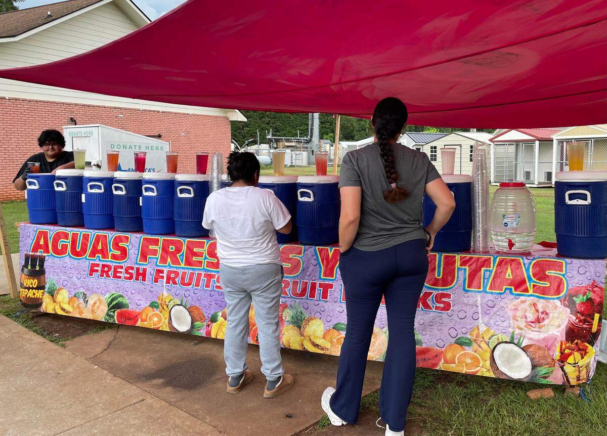 Nathan Ortiz pours a cup of tepache agua fresca made with fermented pineapple at the Aguas Frescas Los Cholos stand at Dunbar and N. Houston Lake roads in Warner Robins as customers wait for their drinks.