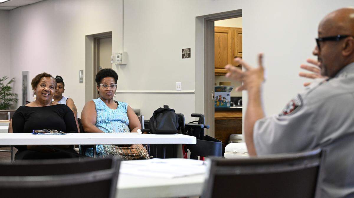 Pendleton Homes residents Marie Charles (left) and her daughter Keisha Spann listen to Bibb County Sheriff’s Office Lt. Chris Dunn during a monthly Pendleton Homes Neighborhood Watch meeting on Thursday, Aug. 21, 2025, in Macon, Georgia. Pendleton Homes has seen the most crime reports out of all properties in the Macon Housing Authority since 2020, but has seen a significant decrease this year. 