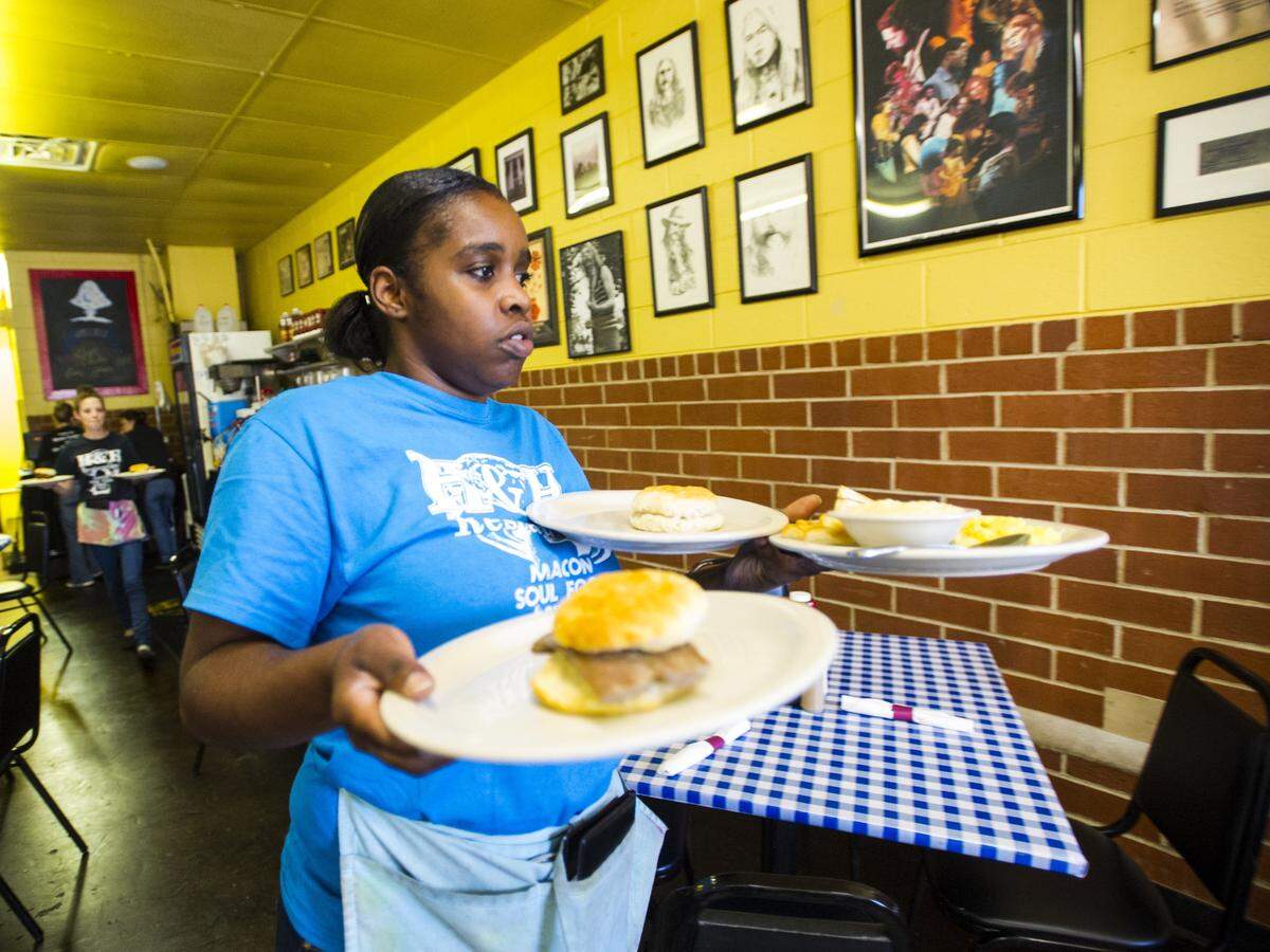 Dominique Jackson delivers food as she serves customers at H&H restaurant.