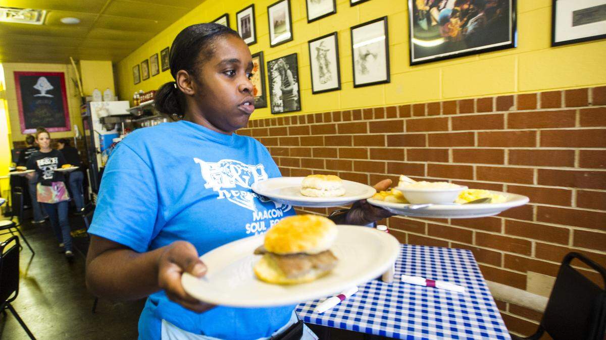 Dominique Jackson delivers food as she serves customers at H&H restaurant.