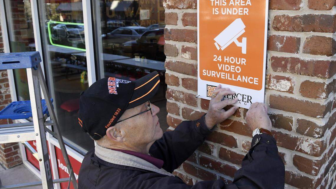 Britt Smith, with Mercer University's physical plant, installs a sign warning of security cameras in Mercer Village.