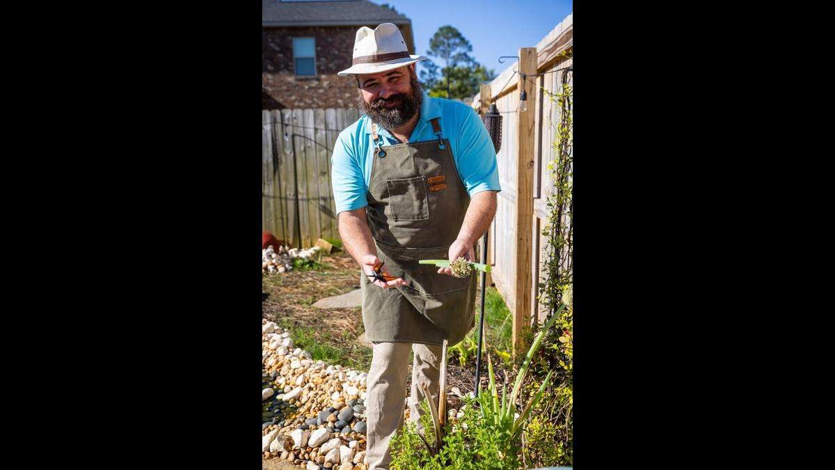 John Staurulakis, owner of Trattori di Napoli, cuts green onions in his backyard in Perry.