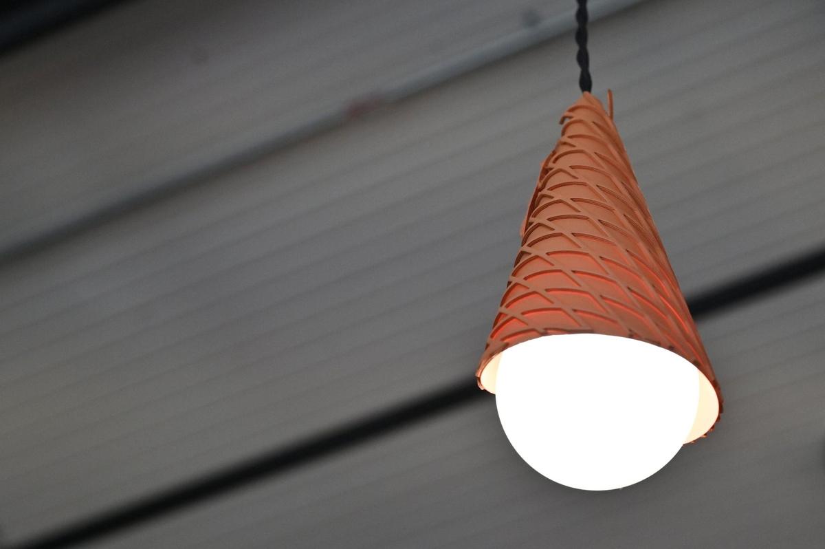 A hanging light wrapped in a waffle cone hangs from the ceiling inside of Shuster’s Candy and Creamery on Friday, July 18, 2025, in Macon, Georgia. Shuster’s co-owner and Mercer University graphic design professor Tennille Shuster designed the light covers, as well as the wallpaper and merchandise for the new ice cream and sweets shop.