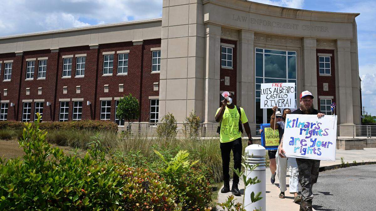Jesse Goolsby (right), from Perry, Georgia, carries a sign with other protesters in from the Warner Robins Law Enforcement Complex during a march down Watson Boulevard on Wednesday, April 30, 2025, in Warner Robins, Georgia. Around a dozen people gathered to protest against the Trump administration’s immigration policies.