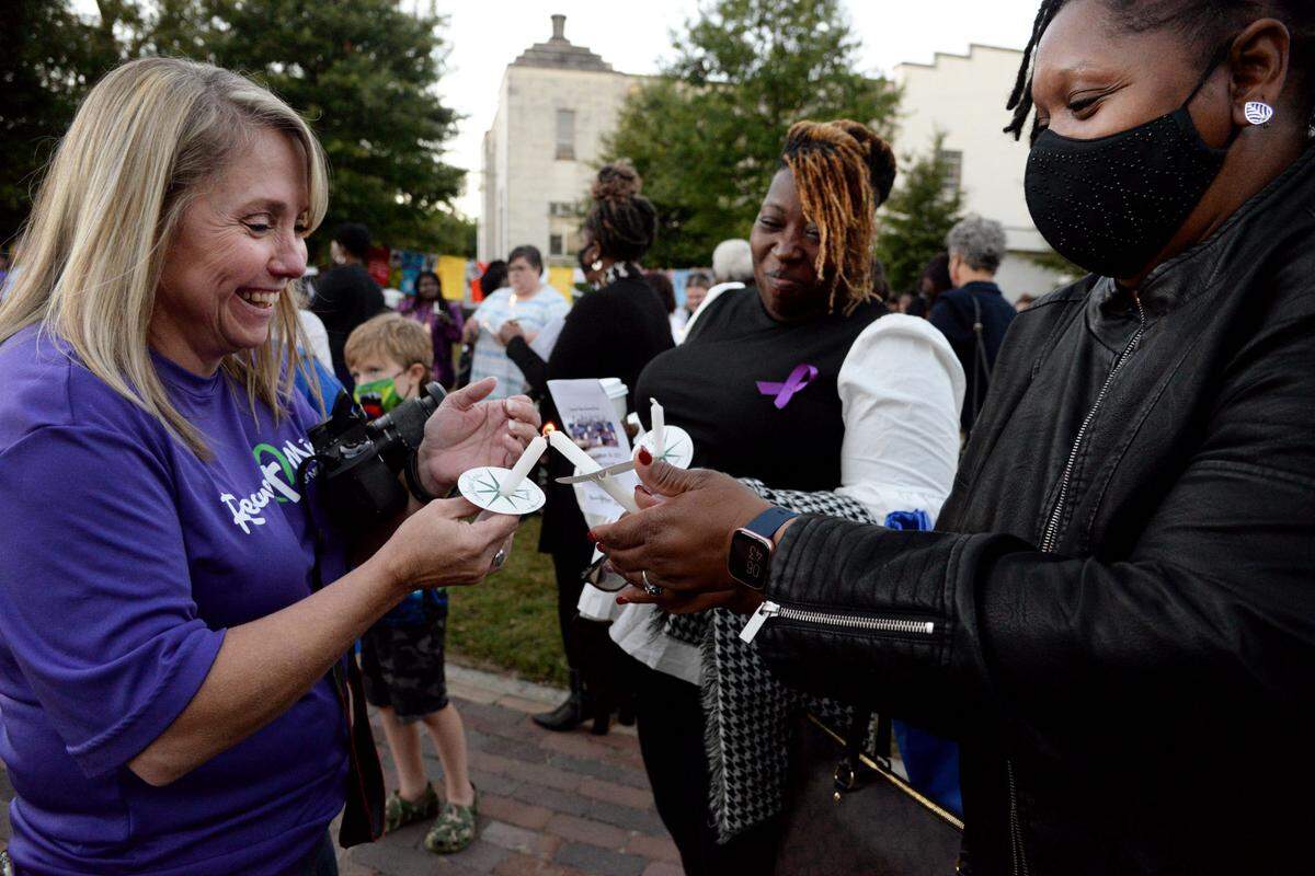 Dawn Burns, the vice president of operations of the Rescue Mission of Middle Georgia, (left) laughs as she tries to light Matred Conaway’s candle (right) again after the wind blew it out.