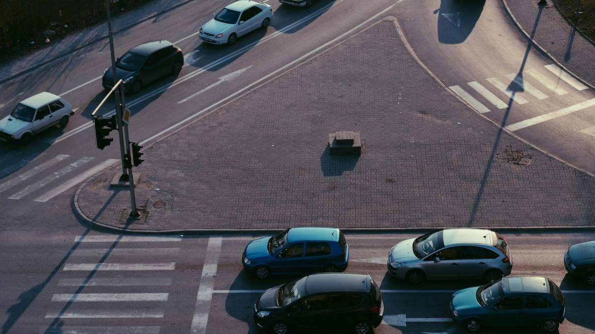 Changing lanes in the middle of the intersection could lead to tickets, accidents where you’re at fault, or potential license suspension. | Cars lined up on a two-lane road in front of an intersection