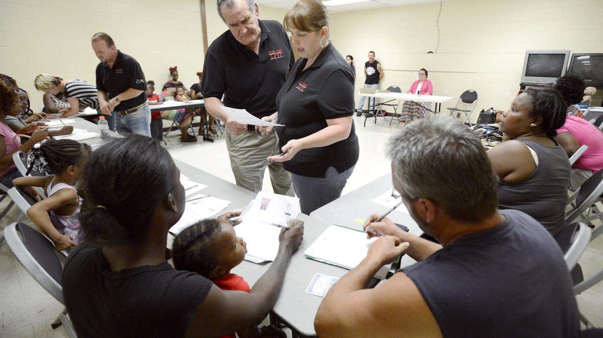 Kids Yule Love CEO Joe Allen and director of Jones County Spring Craven look over an application during a registration event Thursday night at the Bloomfield Recreation Center.