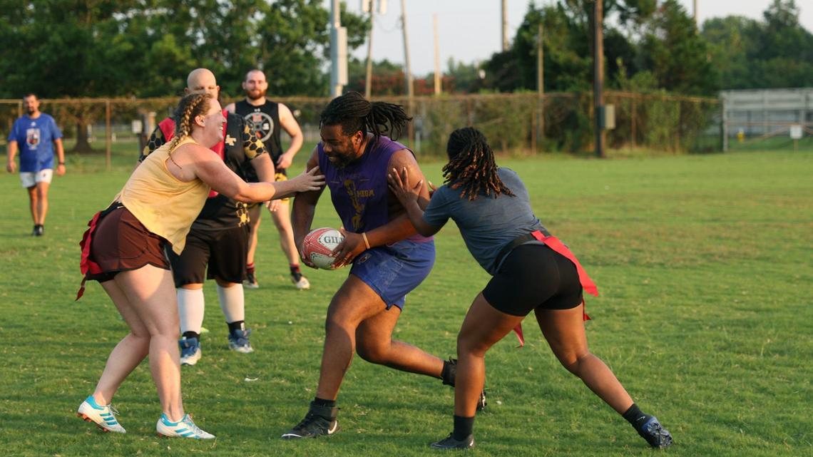Anna Richards (left) and Brianna Cromartie (right) attempt to stop DJ Eackles during a game of touch during Macon Love Rugby practice on Thursday, Aug. 8, 2024, in Central City Park in Macon, Georgia. Macon’s amateur rugby team is expanding their team by competing with an all-female team at a summer competition this weekend.