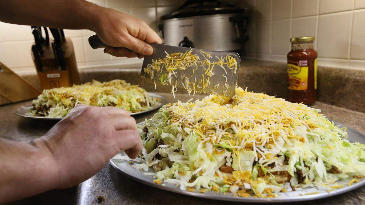 Fire/medic Joe Vaccaro uses a butcher's knife to cut slices in a Taco Pizza as he prepares dinner for seven firefighters at the Mehlville Fire Protection District Engine House No. 5 in St. Louis, Missouri.