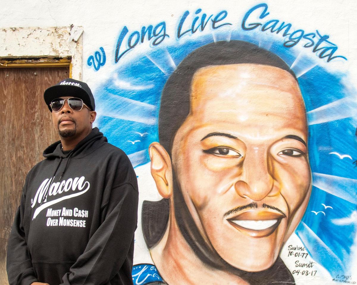 Local artist Carl Dudley Jr. stands out front of a mural he painted of Andre Taylor along Montpelier Avenue. Taylor was shot to death in the M&M Grocery parking lot in April 2017.