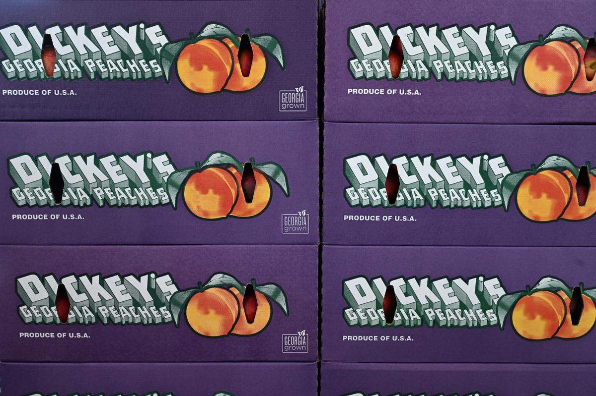 Boxes of Dickey Farms peaches sit inside of the Dickey Farms packing house on Friday, May 9, 2025, in Musella, Georgia. The majority of Dickey Farms peaches are distributed to grocery stores, while a small portion are sold directly from their packing house.