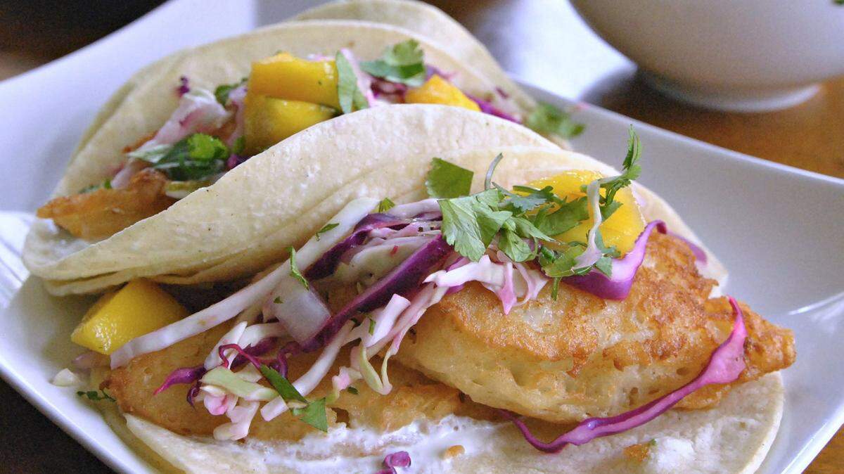 Baja-style Fish Tacos feature soda-battered cod topped with spicy-sweet mango salsa.