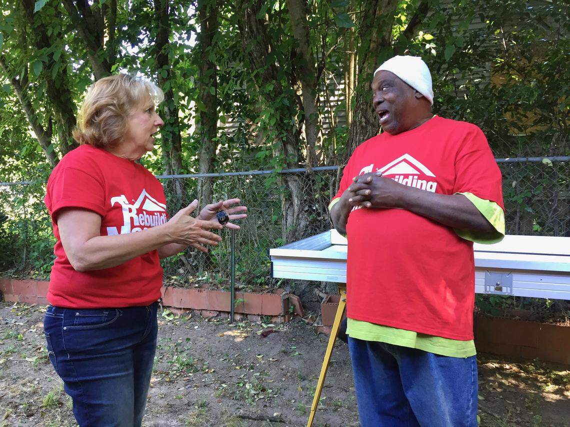 Executive Director of Rebuilding Macon Debra Rollins, left, chats with homeowner Gary Higgins, right, as volunteers repair his back door during the organization’s annual Macon Rebuilding Day April 27, 2019.