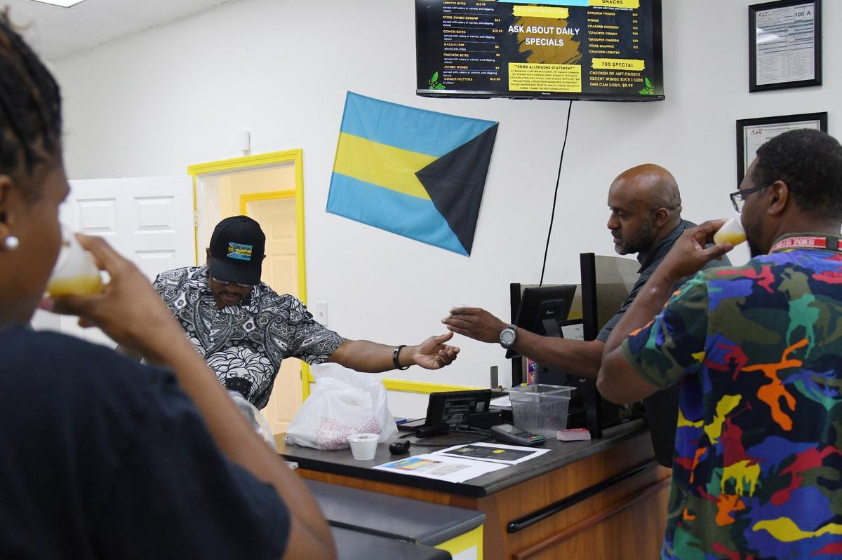 Bahamas Caribbean Cuisine co-owner Walt Williams (left) gives out samples of Bahama signature drink “BCC Juice” on Thursday, Aug. 15, 2024, in Warner Robins, Georgia. The new restaurant serves authentic Bahamian food.