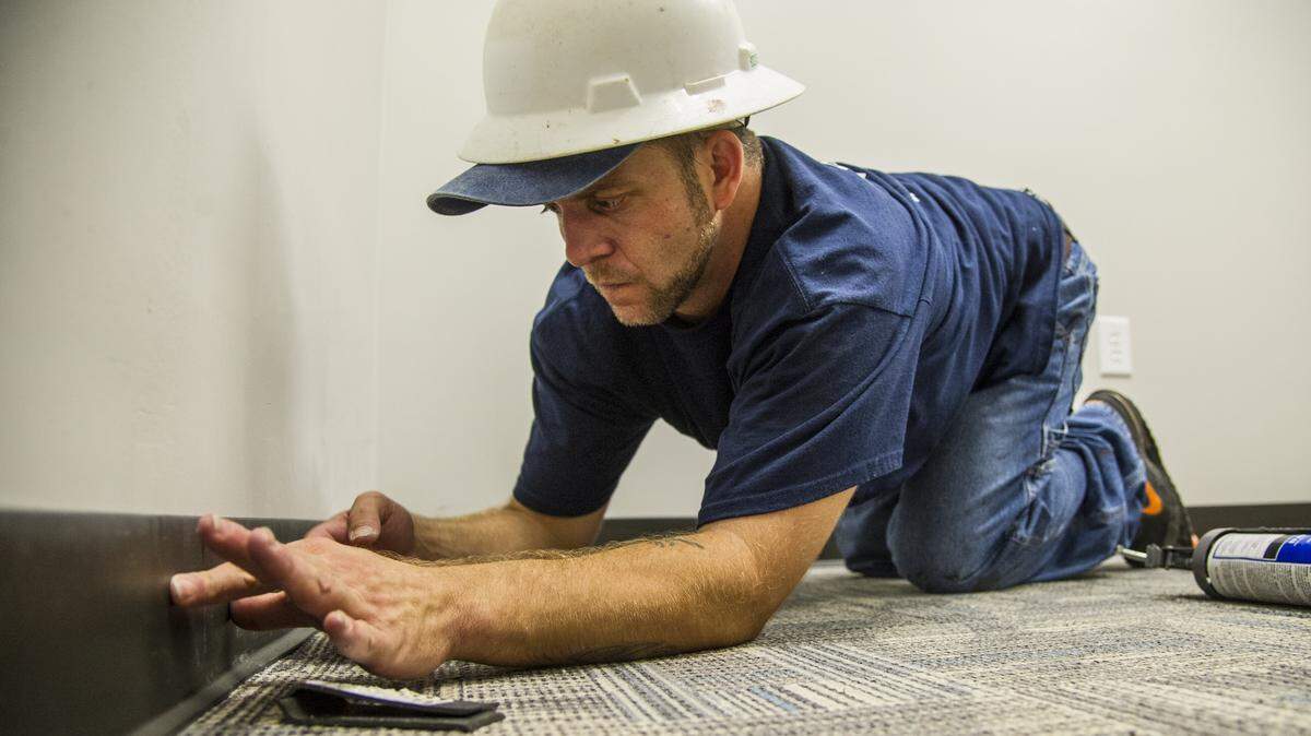 Flooring installer Shawn Allen puts cove base around the floor of an interior office at the former Sears building at the corner of Third Street and Riverside Drive. The building will be the Bibb County Sheriff's Office building.
