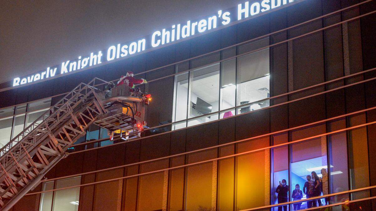 Santa Claus and The Grinch wave at neonatal nurses from a Macon-Bibb County fire truck at Atrium Health Navicent Beverly Knight Olson Children’s Hospital, which has now been renamed to Atrium Health Levine Children’s Beverly Knight Olson Children’s Hospital