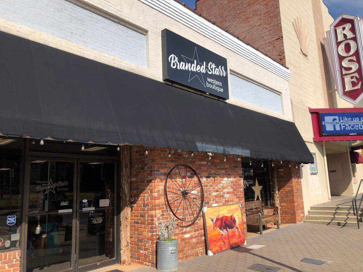 A cow painting and wagon wheel adorn the outside of Branded Starr, a Western-themed boutique in Forsyth that opened in 2022.