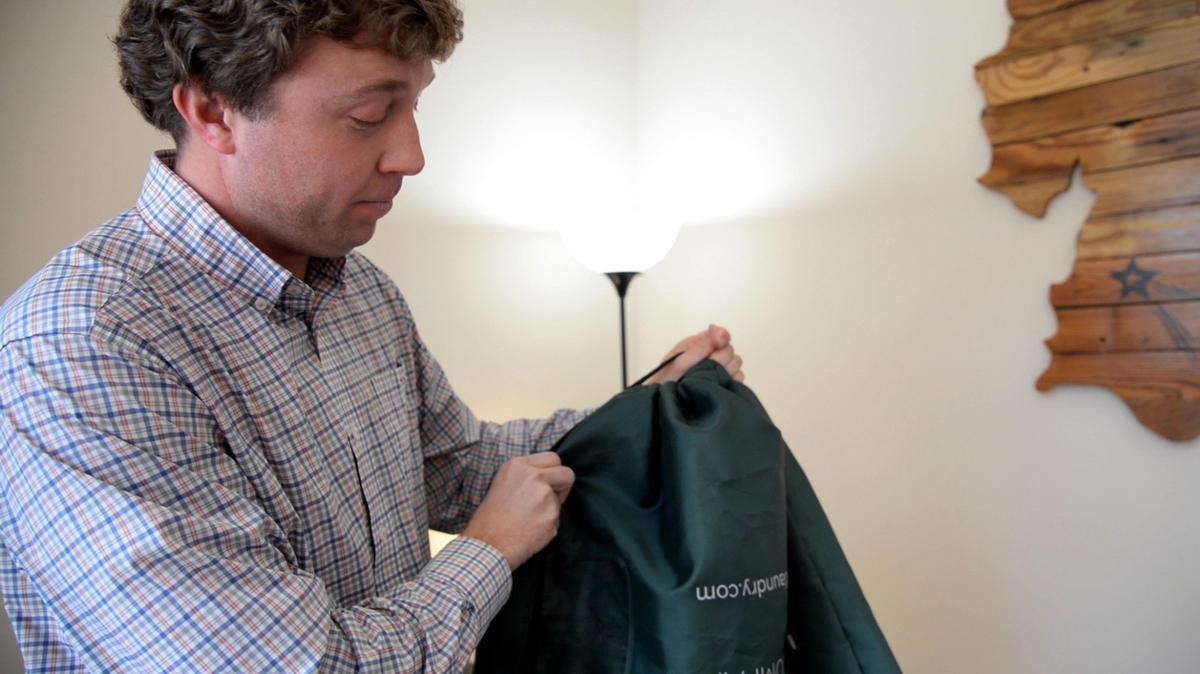 Mitchell Perry, founder of Independent Laundry Company, shows how the laundry bag people receive when they sign up for Independent Laundry Company services can be used for hanging dry cleaning and carrying a sack of laundry.