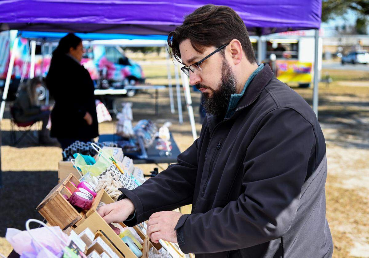 Joshua Hess, owner of The Sassy Alpaca, adjusts some of his product at his booth Thursday at the International City Farmer’s Market in Warner Robins. Hess is about to open a storefront in Macon.