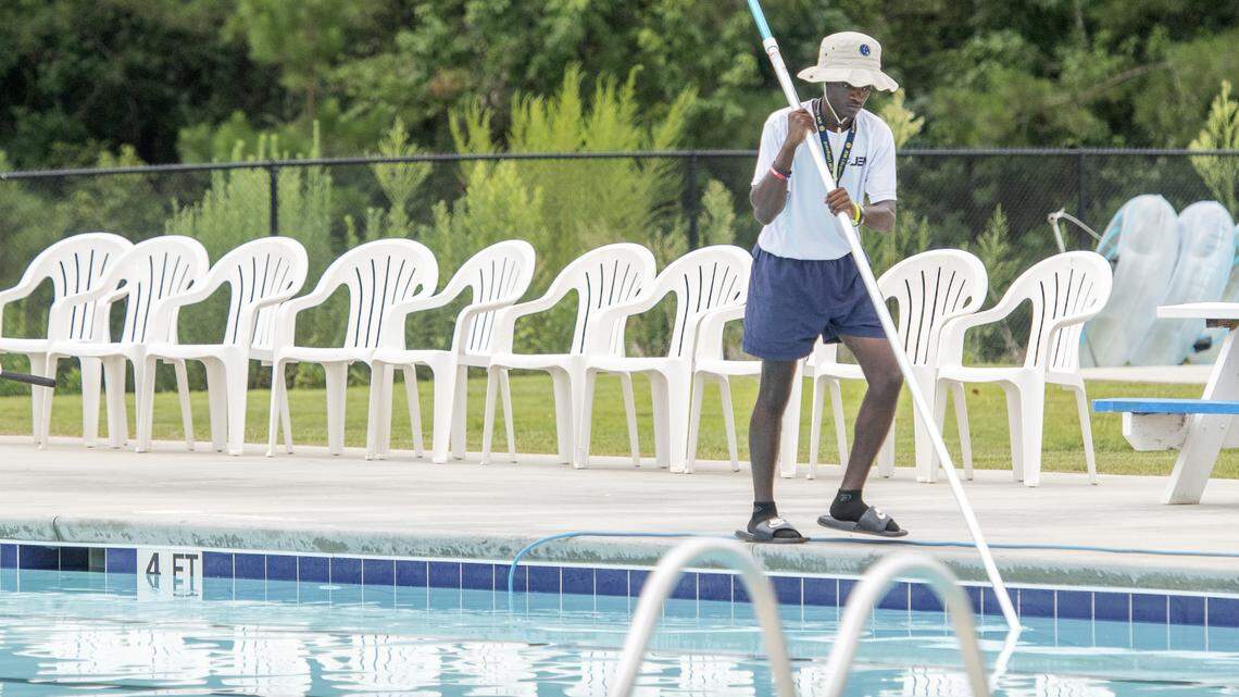 An employee skims the junior Olympic lap pool at Sandy Beach Water Park Monday morning prior to opening.