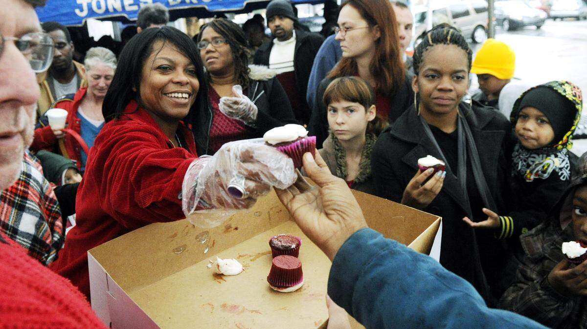 Anita Ponder hands out cupcakes to guests at the 16th Annual Anita Ponder & Friends Holiday Feast outside of Molly's Cafe Sunday afternoon.
