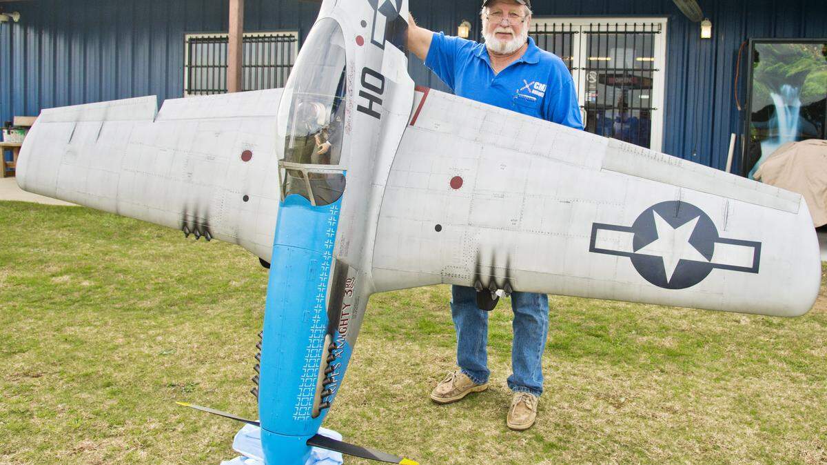 Chuck Walker, co-owner of CMJ Hobbies, holds his 1/3 scale P-51 Mustang in front of his shop in Roberta.