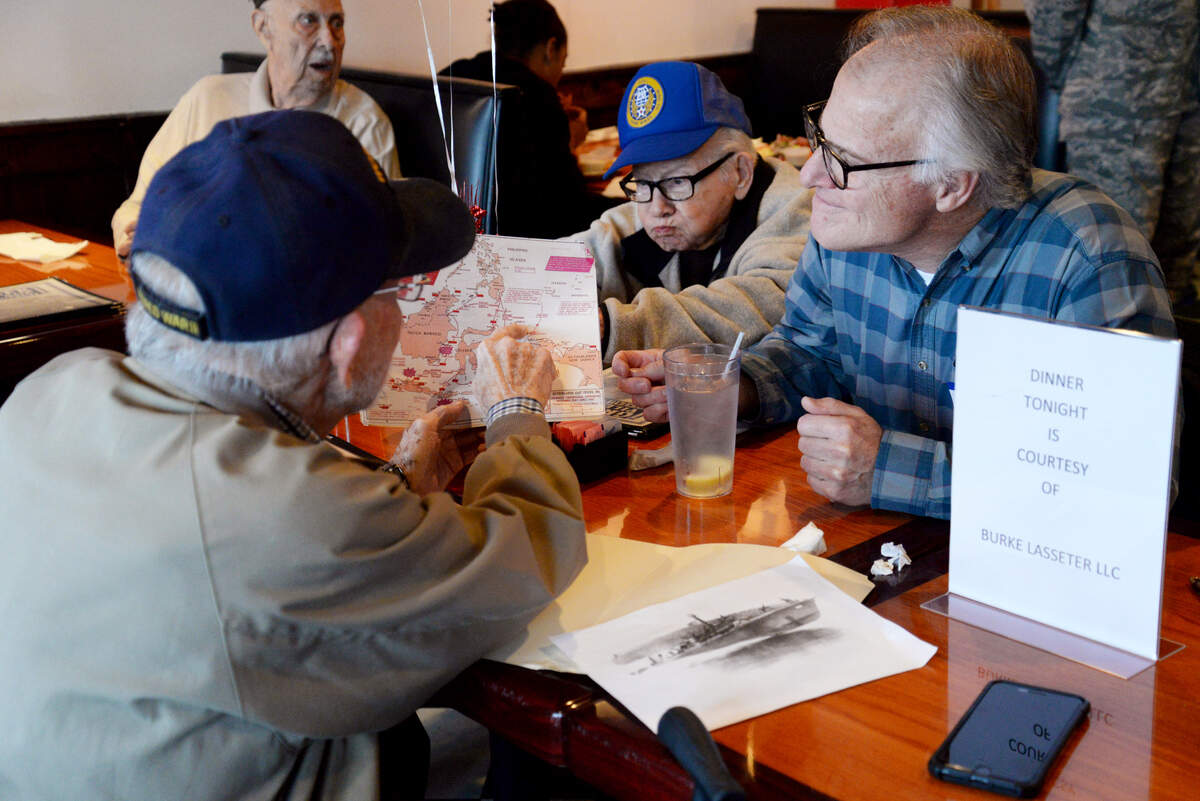 Charles Tyler, in the U.S. Navy during World War II, shows a map to Donald Garrett and his son, Brent, left to right, about where Tyler’s ship was in the southwest Pacific Ocean during the war. Nine World War II veterans were invited to Greek Village in Warner Robins for a dinner hosted by the Warner Robins chapter of the Daughters of the American Revolution to honor their service.