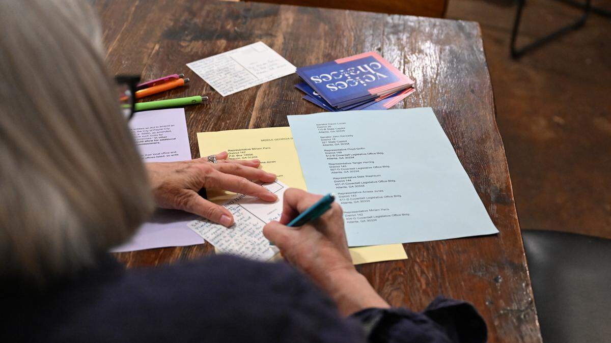Macon-Bibb County Democratic Committee volunteer Kathy Roche writes a postcard to Middle Georgia state representatives at the New Voices, Better Choices post carding event on Tuesday, Nov. 18, 2025, at Just Tap’d Macon in Macon, Georgia. The event focused predominantly on advocating for mayoral term limits in Macon. 