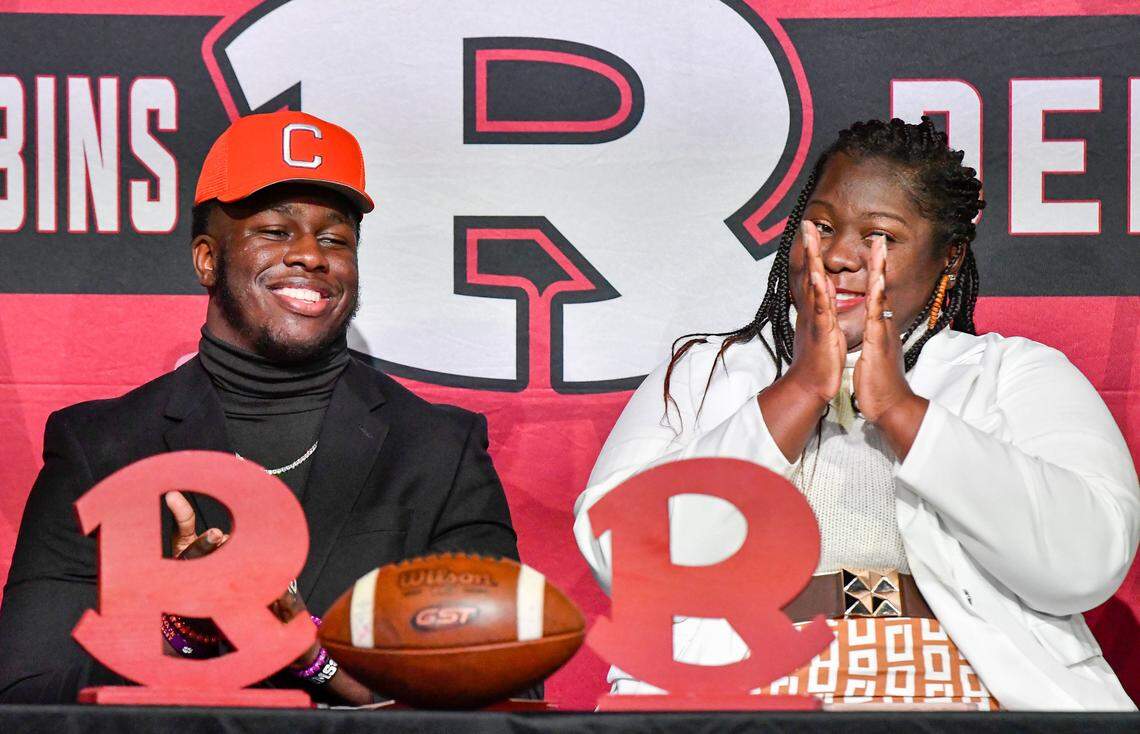 Warner Robins senior defensive end Vic Burley cracks a smile as his mother Heather Burley applauds after signing his National Letter of Intent with Clemson in the school’s auditorium Wednesday morning.