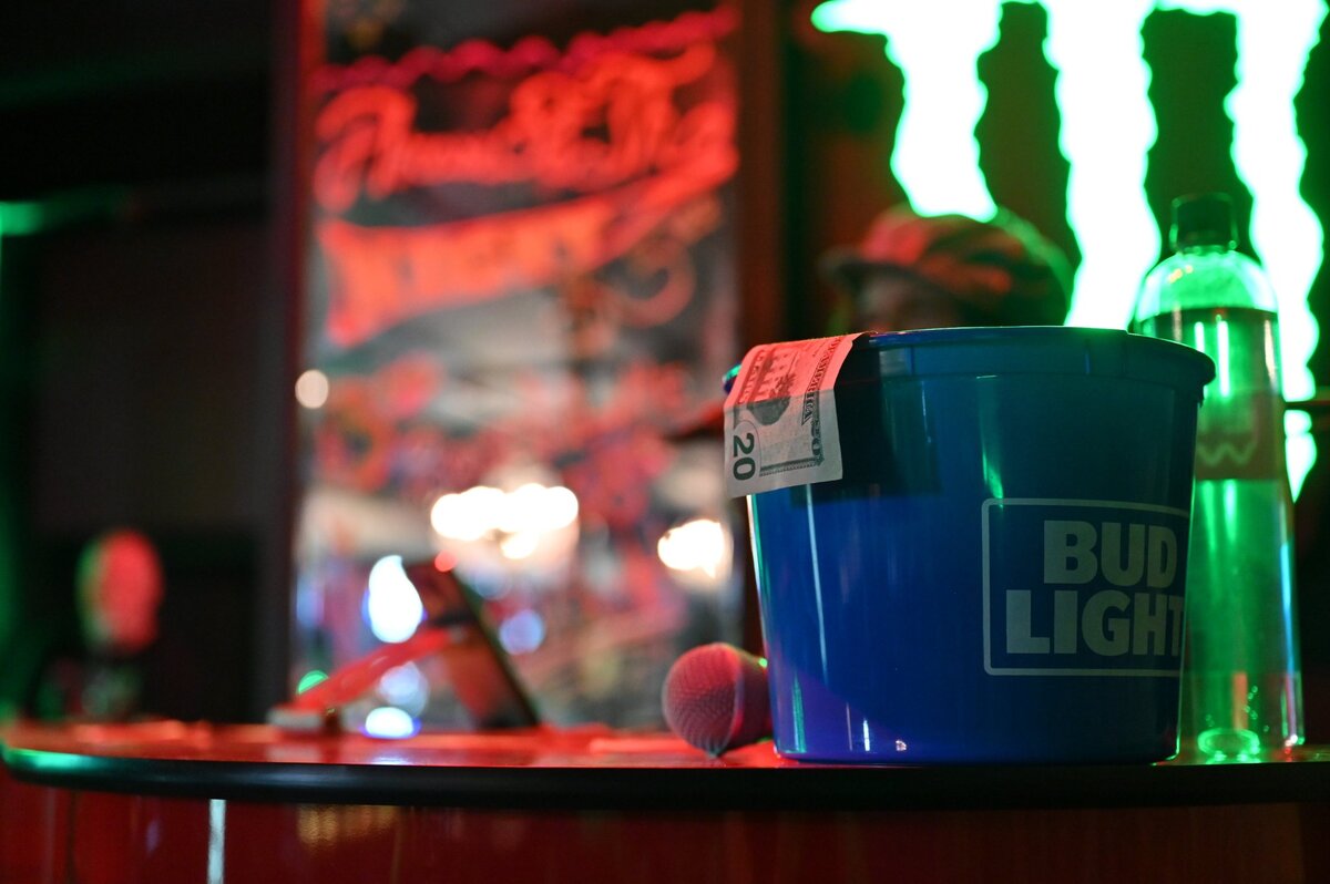 A $20 bill hangs out of the bucket where the visiting pianists accept tips attached to song requests on Friday, May 16, 2025, at 5ive70 Dueling Piano Bar in downtown Macon, Georgia. The new bar and live music venue features two pianists every weekend that play exclusively audience requested tunes of any genre.
